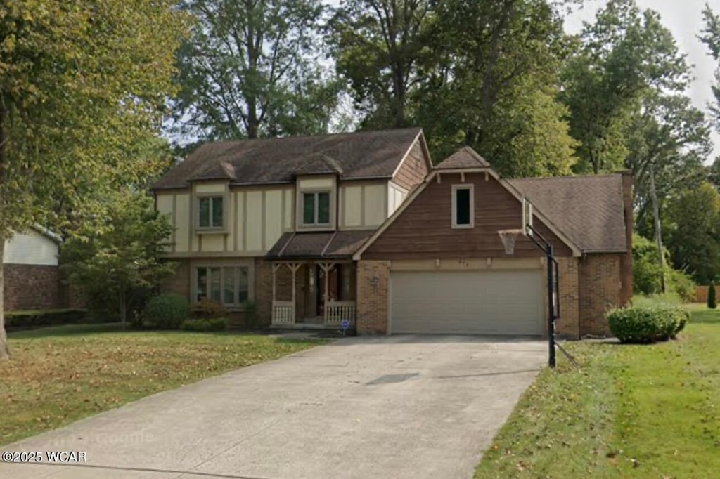 619 Tall Oaks Ave, Lima, OH 45805 - english style home featuring concrete driveway, a front lawn, a garage, and brick siding