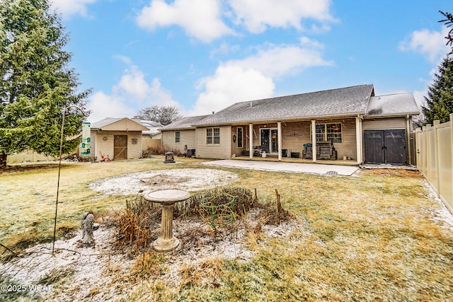 back of property with a shed, a patio area, and a lawn