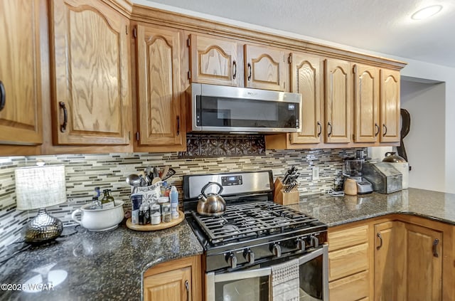 kitchen with tasteful backsplash, stainless steel appliances, and dark stone counters