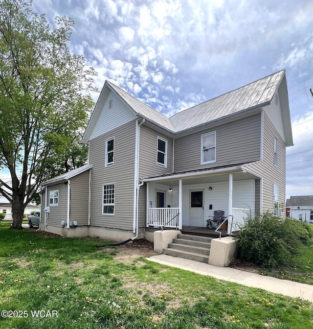 view of front of property with a porch, a front lawn, and metal roof