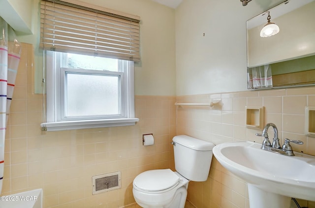 bathroom featuring toilet, sink, and tile walls