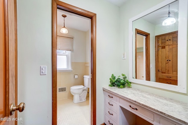 bathroom featuring tile walls, vanity, and toilet