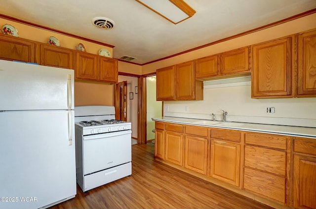 kitchen with sink, white appliances, and light hardwood / wood-style flooring