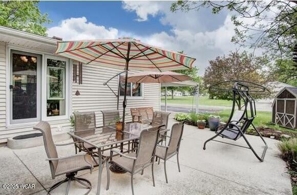 view of patio featuring outdoor dining area, a storage shed, and an outdoor structure