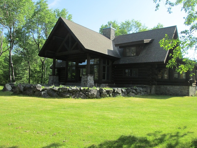 back of house featuring log siding, a yard, roof with shingles, and a chimney