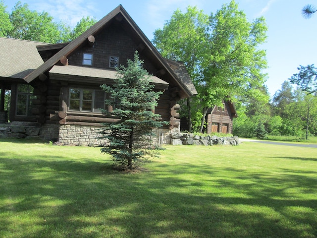 view of home's exterior with log siding, an outbuilding, and a yard