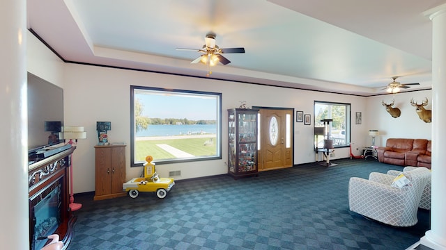 living area with visible vents, a fireplace, a ceiling fan, and dark colored carpet