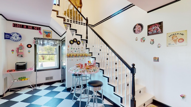 stairs with tile patterned floors, visible vents, baseboards, and a high ceiling