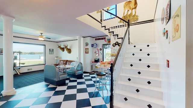 interior space featuring tile patterned floors, a wealth of natural light, a ceiling fan, and ornate columns