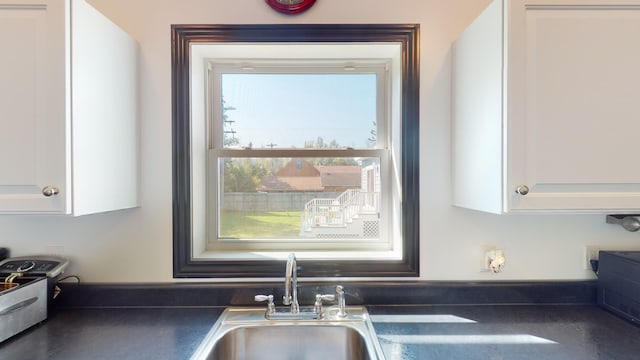 kitchen with dark countertops, white cabinets, and a sink