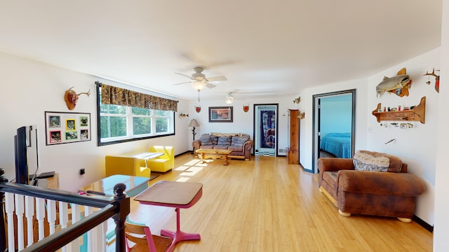 living area featuring ceiling fan, baseboards, and light wood-style flooring