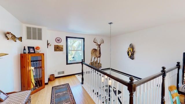 corridor featuring light wood-style flooring, an upstairs landing, visible vents, and baseboards