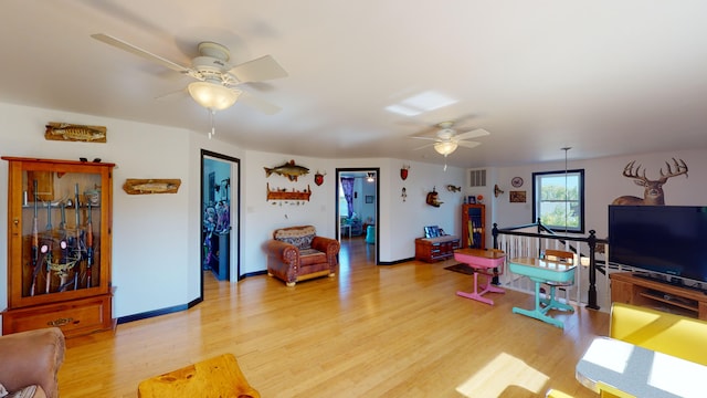 living room featuring baseboards, visible vents, light wood finished floors, and ceiling fan