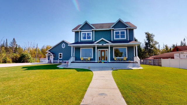 view of front facade with covered porch, a front yard, and fence