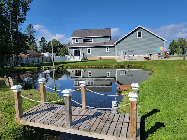 view of dock featuring a water view, a yard, and fence