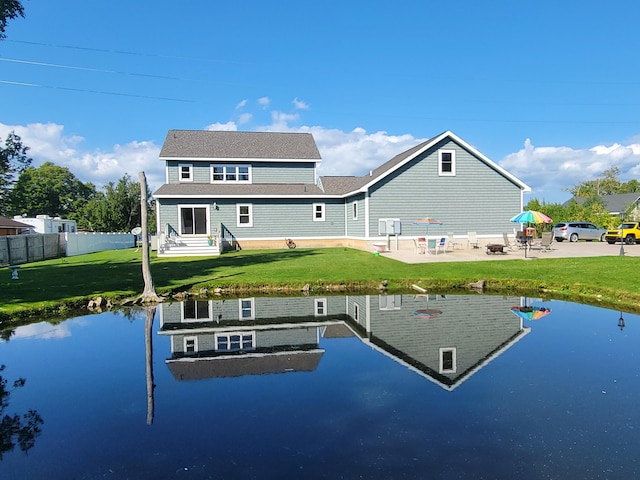 back of house with a patio area, fence, a lawn, and a water view