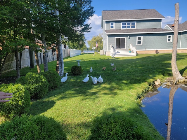 rear view of property featuring a lawn, entry steps, and fence