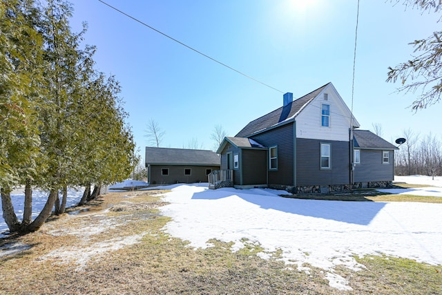 snow covered rear of property with a chimney