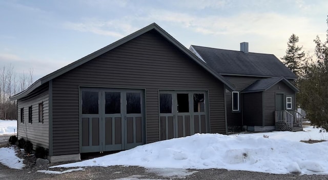 snow covered rear of property featuring a garage