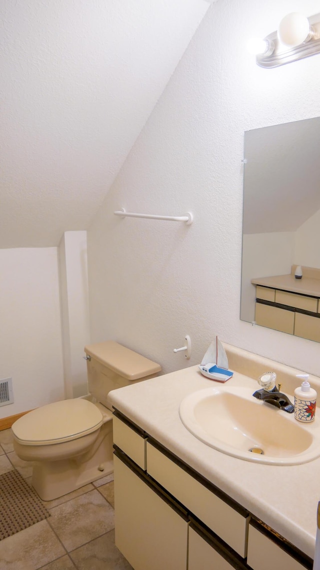 half bathroom with tile patterned flooring, lofted ceiling, toilet, and vanity