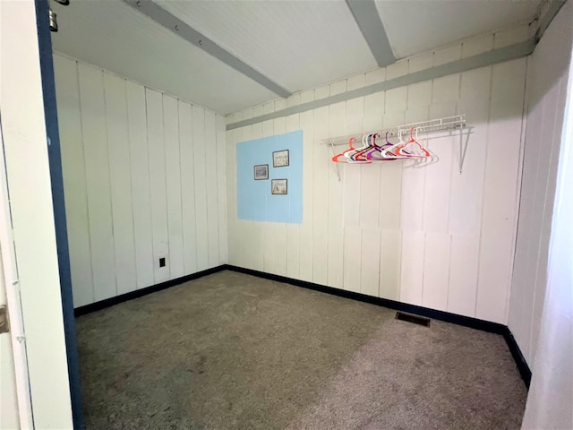 carpeted spare room with visible vents, beam ceiling, and baseboards