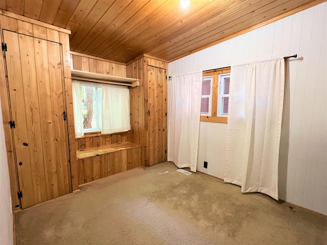 carpeted spare room with wooden ceiling, wooden walls, and visible vents