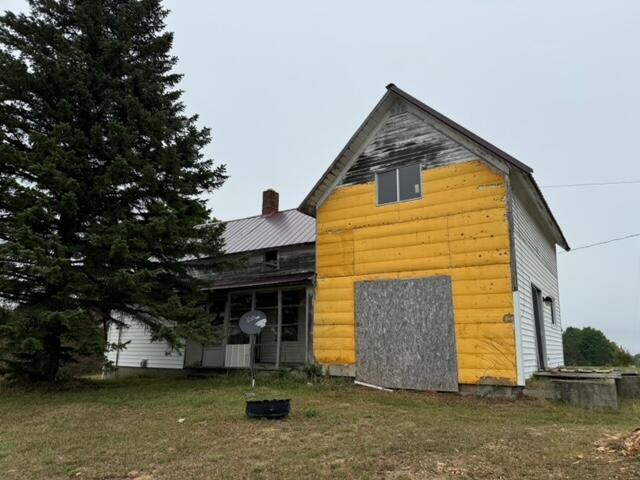 rear view of house with a lawn and log veneer siding