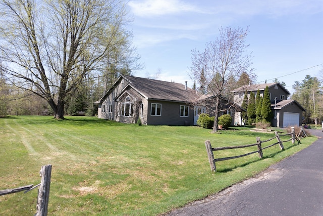 view of front of house featuring a front lawn, fence, a garage, and aphalt driveway