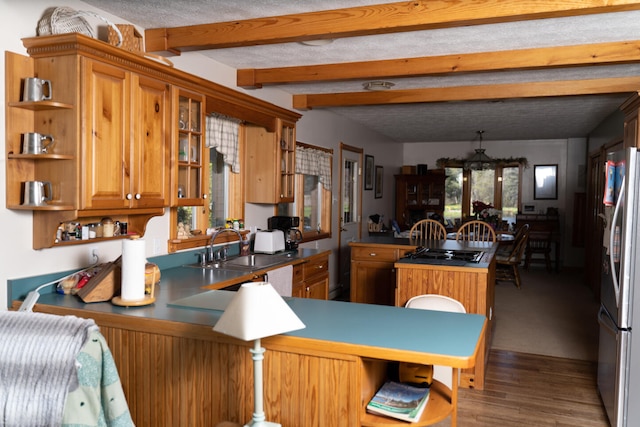 kitchen with beam ceiling, open shelves, freestanding refrigerator, a peninsula, and brown cabinetry