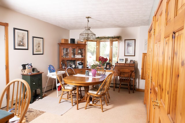 dining space featuring light carpet, baseboard heating, and a textured ceiling