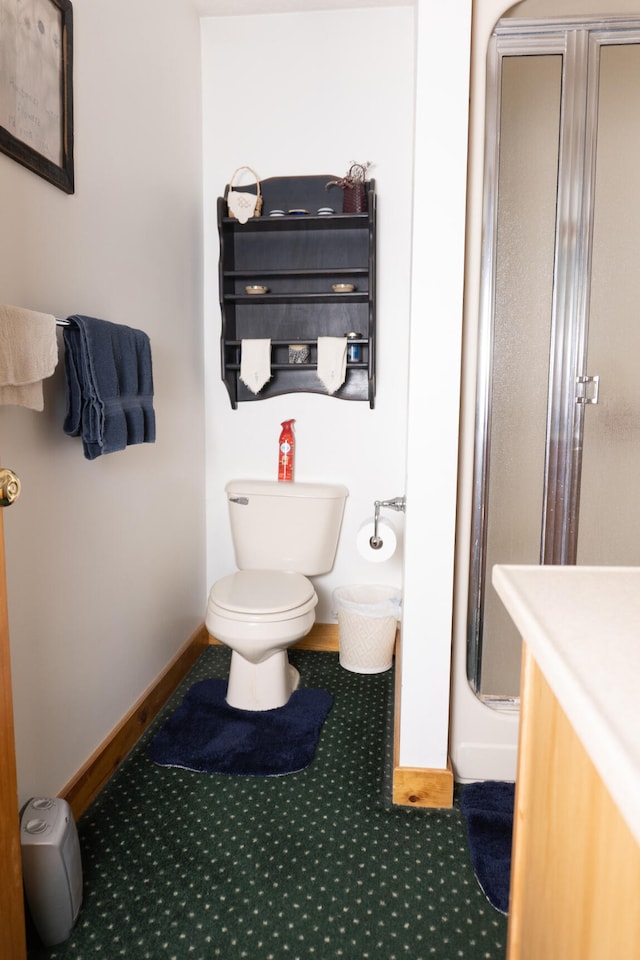 bathroom with vanity, toilet, baseboards, and a stall shower