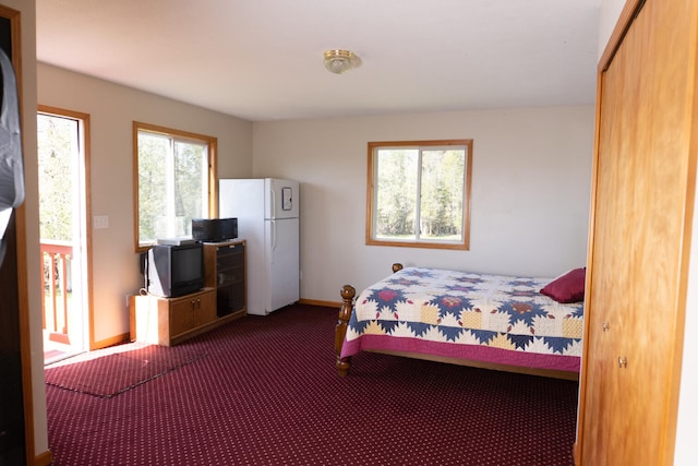 carpeted bedroom featuring baseboards and freestanding refrigerator