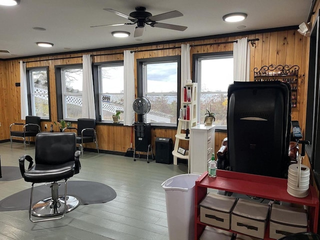 home office with wooden walls, a ceiling fan, and wood-type flooring