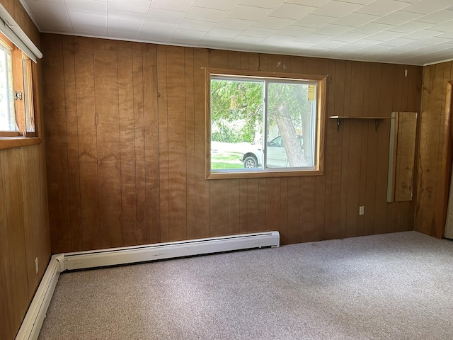 carpeted empty room with wooden walls and a baseboard radiator