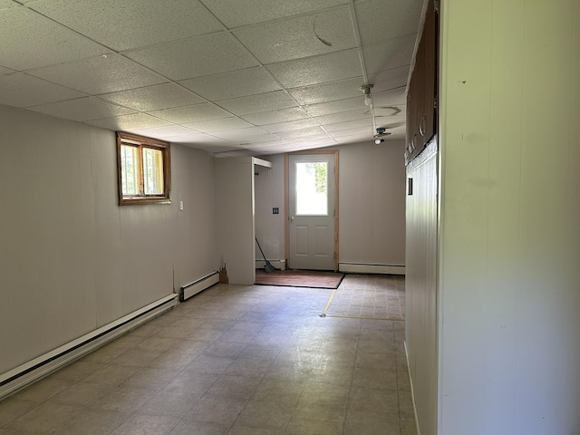 basement with a wealth of natural light, a baseboard heating unit, and a baseboard radiator