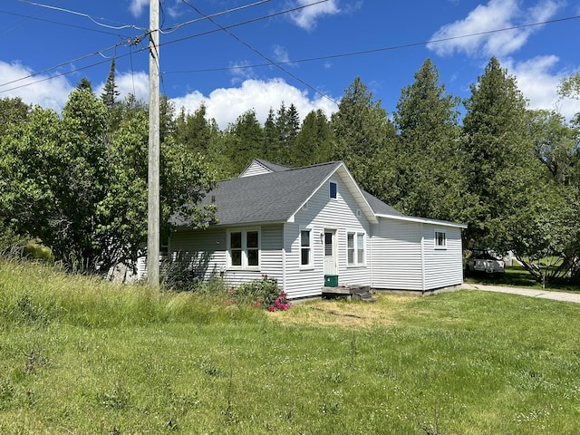 exterior space with a front lawn and roof with shingles