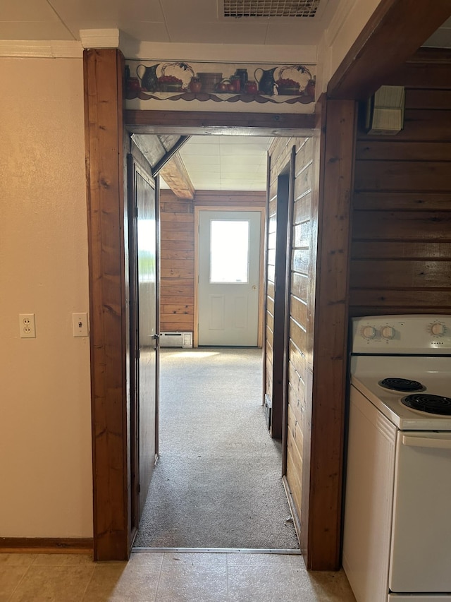 hall featuring baseboards, visible vents, a baseboard radiator, wood walls, and light carpet