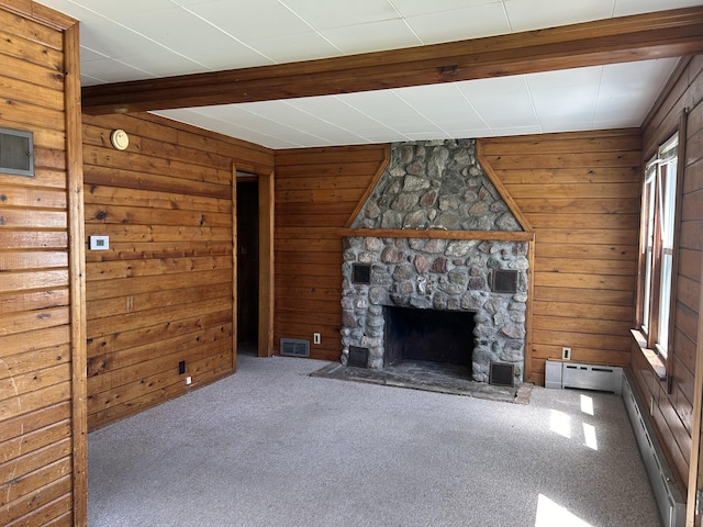 unfurnished living room with visible vents, beam ceiling, carpet floors, wood walls, and a fireplace