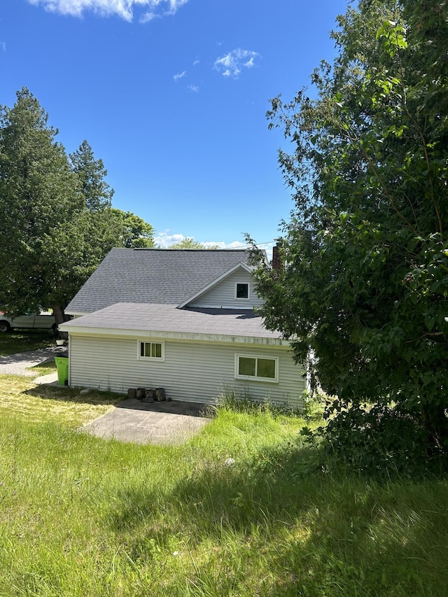 view of side of property featuring roof with shingles and a patio area