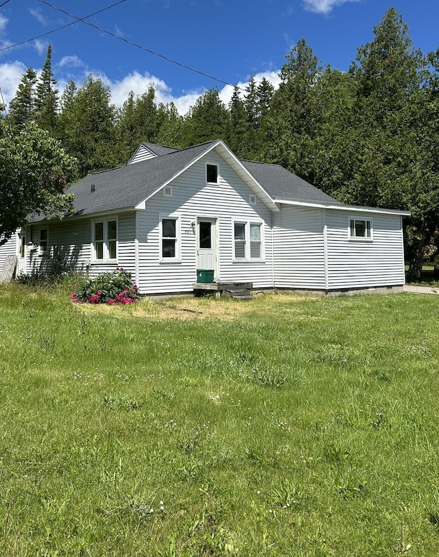 rear view of house featuring a lawn and a shingled roof