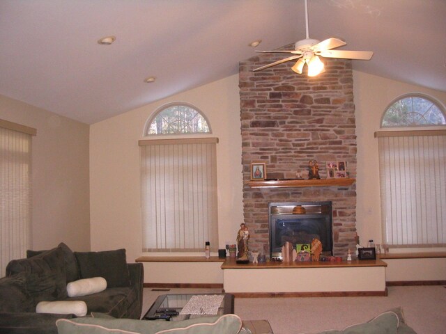 living room with a stone fireplace, vaulted ceiling, and a ceiling fan