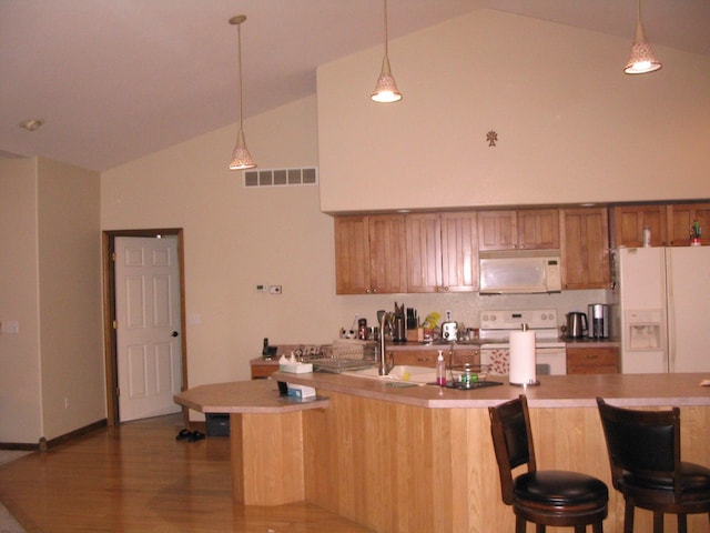 kitchen with visible vents, pendant lighting, white appliances, high vaulted ceiling, and a sink