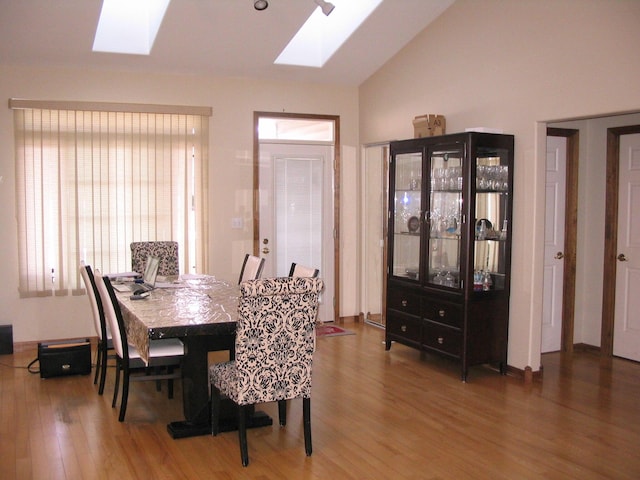 dining room with lofted ceiling with skylight and wood finished floors