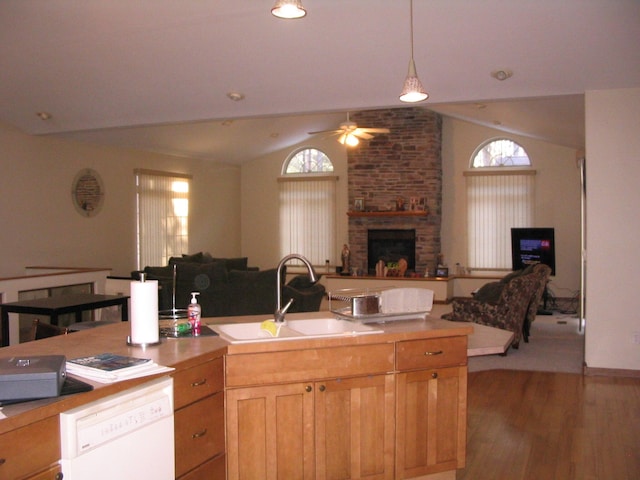 kitchen featuring open floor plan, vaulted ceiling, a fireplace, white dishwasher, and a sink