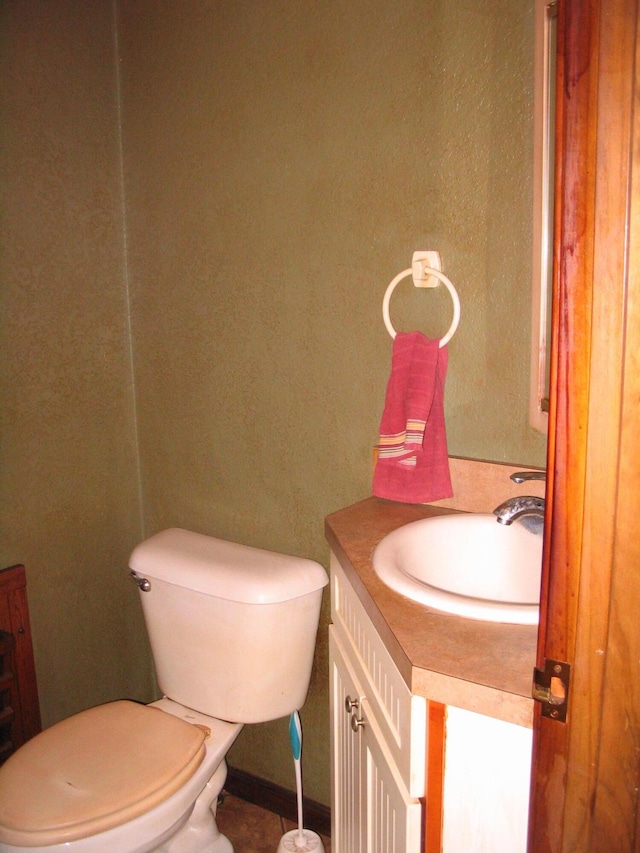 bathroom featuring toilet, vanity, and baseboards