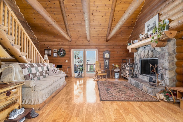 living area featuring stairway, wood finished floors, a stone fireplace, wooden ceiling, and beamed ceiling