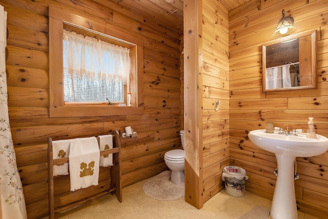 full bath featuring tile patterned floors, toilet, and wood walls