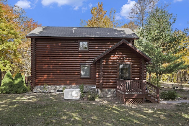 back of property with log siding, a lawn, and roof with shingles