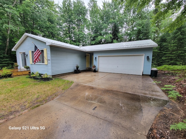 ranch-style home with concrete driveway, metal roof, a garage, and a front yard