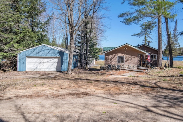 view of yard featuring a detached garage, an outbuilding, and dirt driveway